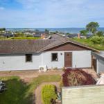 Ein Haus mit Garten und Meerblick. Terrasse, Pflanzen und Blick auf das Wasser.