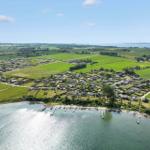 Aerial view of coastal village with green fields and water access.