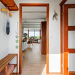Haus mit Holzfußboden und Tür, Blick in Wohnzimmer mit Sofa und Stühlen.