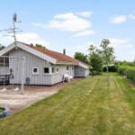 Ein Ferienhaus mit Garten, Schaukel und Terrasse unter blauem Himmel.