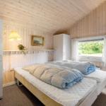 Schlafzimmer mit Holzwand, Bett, Fenster und Schrank.