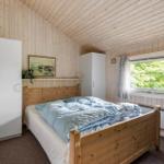 Schlafzimmer mit Holzwand, Bett, Fenster und Schränken.
