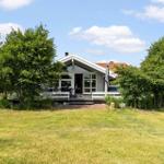 Ein Haus mit Terrasse und Garten unter blauem Himmel.