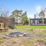 Haus mit großem Garten, Feuerkorb und Holzbank im Freien.
