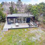 Moderne Hütte mit großem Holzdeck, Garten und Bäumen umgeben.