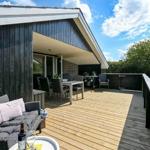 Terrasse mit Sitzgruppe, Tisch und Grill. Holzdecke, Garten und Himmel.