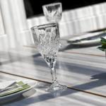 Glas, Teller und Besteck auf einer Terrasse mit Pflanze.