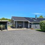 Ein graues Ferienhaus mit Terrasse, Grillplatz und Garage für Boot.