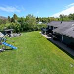 Großer Garten mit Spielplatz, Grill und Terrasse neben dem Haus.