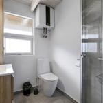 Badezimmer mit Dusche, Toilette und Waschbecken. Fenster und Heizung sichtbar.