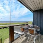 Terrasse mit Tisch und Stühlen, Blick auf Wasser und Strand.