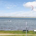 Kitesurfer auf dem Wasser mit rotem Segel im Himmel.