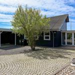 Ein dunkelblauer Ferienhaus mit Garage und Steinweg unter blauem Himmel.