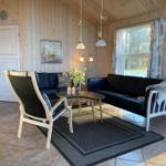 Wohnzimmer mit Holzwand, zwei schwarzen Sofas, einem Stuhl und einem Tisch.
