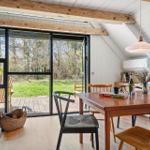 Essbereich mit Holztisch, Stühlen und Kamin. Große Fensterfront mit Blick auf Garten.