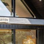 Haus mit Schild KNASTEN, dunkle Holzwand und Fenster mit Blick ins Innere.
