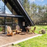 Holzterrasse mit Sitzgelegenheiten vor einem modernen Haus mit großem Glasbereich.