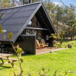 Hütte mit Terrasse, Grill und Picknicktisch im Grünen.
