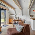 Wohnbereich mit Kamin, Essbereich und Kücheninsel unter Holzbalkendecke.