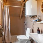 Badezimmer mit Dusche, Toilette und Waschbecken. Holzdecke und -wände.