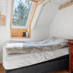 Schlafzimmer mit Dachfenster, Bett und Holzmöbeln.