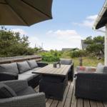 Terrasse mit Sitzgruppe, Tisch und Sonnenschirm. Blick auf Grünflächen und Hauswand.