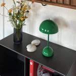 Schwarzer Tisch mit grüner Lampe, Blumen und Muscheln.