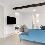 Wohnzimmer mit blauem Sofa, Fernseher und Holzbalken an der Decke.