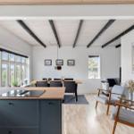 Küche mit Essbereich und Wohnzimmer mit Holzboden und Deckenbalken.