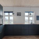 Moderne Küche mit dunklen Schränken, Holzboden und großen Fenstern.