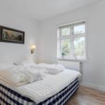 Schlafzimmer mit Bett, Fenster und Wandbild.