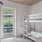 Zimmer mit Doppelstockbett und Fenster zur Terrasse mit Sitzgelegenheit.
