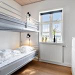 Zimmer mit Doppelstockbett, Fenster, Heizkörper und Schrank.