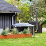 Hinterhof mit Whirlpool, Pflanzenbeet und Garten. Schwarze Holzwand und grünes Gras.
