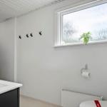 Badezimmer mit Toilette, Waschbecken und Dusche. Fenster mit Pflanze und Haken an der Wand.