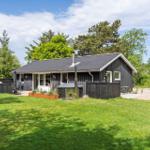 Schwarzes Holzhaus mit Terrasse, Garten und Sauna im Freien.