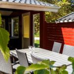 Roter Holzaussenbereich mit Tisch und Stühlen. Tür und Fenster sind sichtbar.