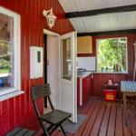 Roter Holzveranda mit Tisch, Stuhl und Blick in Küche.