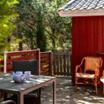 Terrasse mit Tisch, Stühlen und Blick auf grüne Bäume neben rotem Holzhaus.