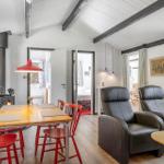 Essbereich mit Tisch und roten Stühlen, schwarze Ledersessel und Kamin im Wohnzimmer.