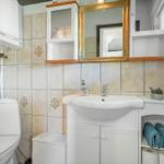 Badezimmer mit Waschbecken, Spiegel, Toilette und Handtüchern.