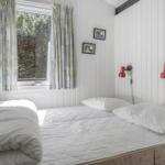 Schlafzimmer mit weißem Bett, Fenster mit Vorhängen und roten Wandlampen.