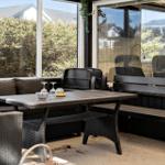 Terrasse mit Tisch, Bänken und Sitzgelegenheiten. Durchgehendes Glasfenster zur Außenseite.