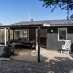 Schwarzes Haus mit Terrasse, Sitzgelegenheiten und Feuerkorb. Durchgang zur Wohnung.