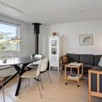 Wohn- und Essbereich mit Sofa, Tisch und Stühlen. Große Fenster und Holzboden.