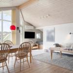 Living and dining area with wooden floor, sofa, dining table, and red pendant lights.