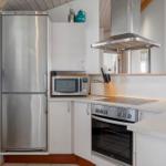 Kitchen with stainless steel fridge and oven, microwave, and range hood.