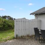 Terrace with table and chairs next to a house with white fence and green area.