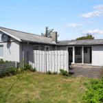 A holiday home with gray wooden facade, terrace, and garden. Satellite dish and barbecue area are available.