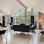 Großes Wohn- und Esszimmer mit Holzdecke, Fenstern und Kamin.